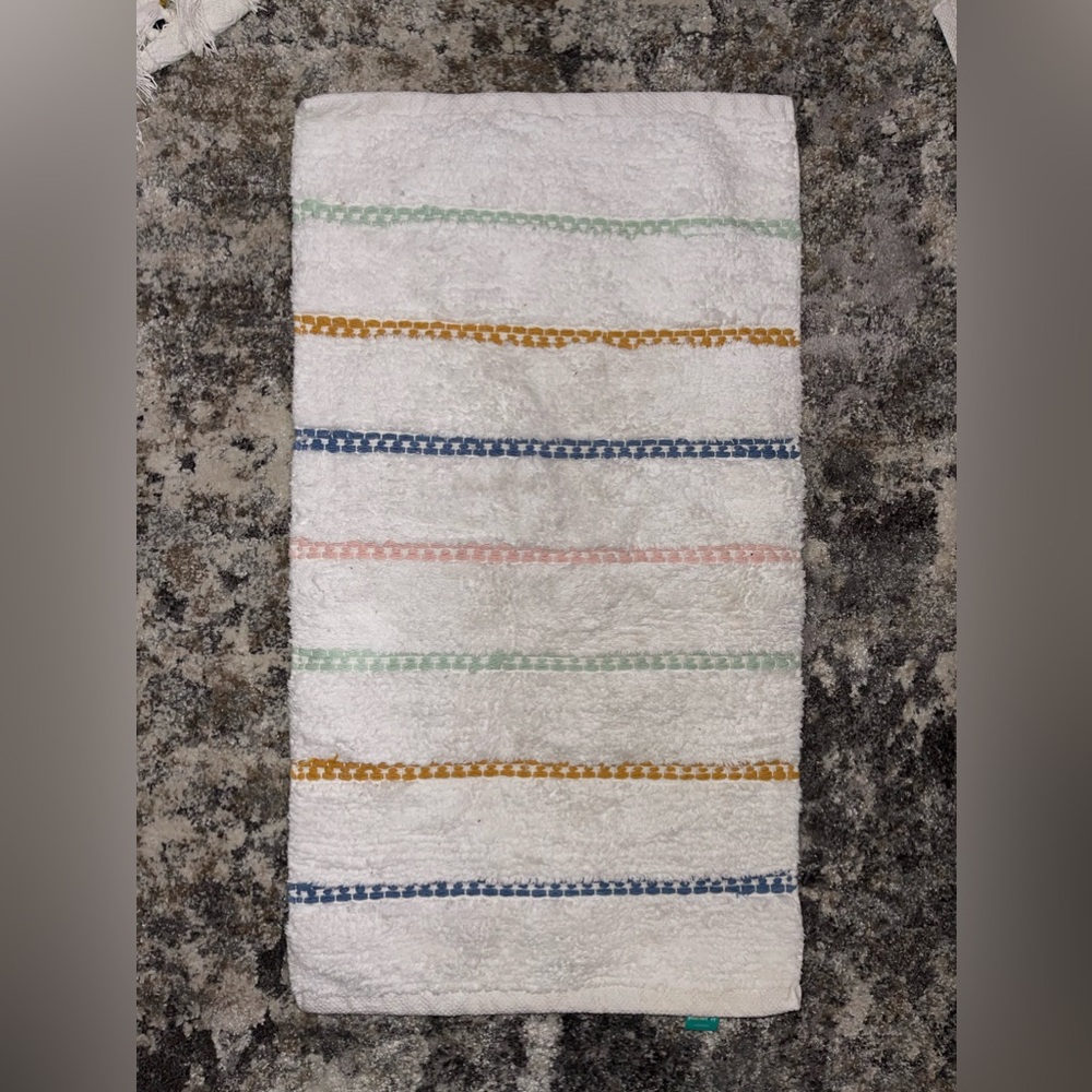 White bathroom rug w/ multicolored threading. Perfect size in front of the sink
